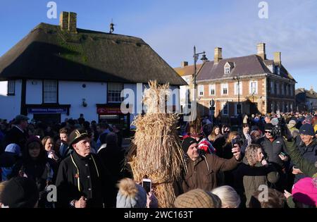 Der Strohbär wird während des Whittlesea Straw Bear Festivals in Whittlesea, Cambridgeshire, begleitet von Pflegern, Musikern und Tänzern durch die Straßen geführt. Bilddatum: Samstag, 13. Januar 2024. Stockfoto