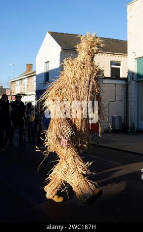 Der Strohbär wird während des Whittlesea Straw Bear Festivals in Whittlesea, Cambridgeshire, begleitet von Pflegern, Musikern und Tänzern durch die Straßen geführt. Bilddatum: Samstag, 13. Januar 2024. Stockfoto