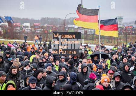 Hohenlockstedt, Deutschland. Januar 2024. Die Teilnehmer einer Demonstration halten deutsche Fahnen und ein Banner mit der Aufschrift "Wir sorgen für Wohlstand, nicht die Politiker". Auf dem Flugplatz Hungry Wolf. Der Schleswig-Holsteinische Baugewerbeverband forderte eine große Demonstration von Bauunternehmen. Quelle: Georg Wendt/dpa/Alamy Live News Stockfoto