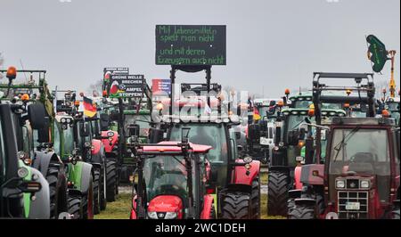 Hohenlockstedt, Deutschland. Januar 2024. Ein Traktor mit dem Banner „man spielt nicht mit Essen und man spielt auch nicht mit den Produzenten“ steht neben vielen anderen Traktoren auf dem Flugplatz Hungry Wolf. Der Schleswig-Holsteinische Baugewerbeverband forderte eine große Demonstration von Bauunternehmen. Quelle: Georg Wendt/dpa/Alamy Live News Stockfoto