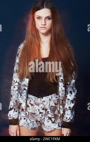 Porträt, Mode und eine ernste junge Frau im Studio auf dunklem Hintergrund für Kleidung. Haare, Flare und intensiv mit einem selbstbewussten rothaarigen Modell Stockfoto