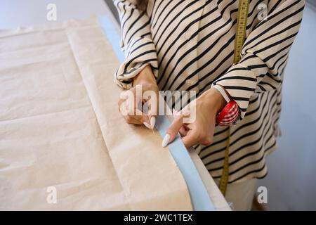 Eine Frau in einer Werkstatt klebt ein Muster an den Stoff Stockfoto