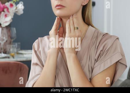 Eine kaukasische Frau, die ihren Hals berührt. Halsschmerzen, Erkältung, Grippe, Tonsillitis oder Schilddrüsenproblem Stockfoto