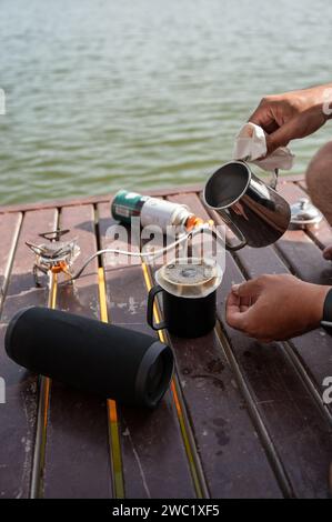 Gießen Sie heißes Wasser aus dem Wasserkocher in gemahlenen Kaffee auf einer Tasse. Morgens tropfenden Kaffee zubereiten Stockfoto