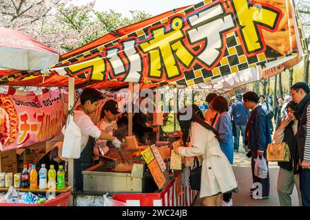 Sehen Sie während des Kirschblütenfestes einen Blick entlang des Fast-Hot-Food-Standes im Osaka Castle Park. Beschäftigt mit mehreren Personen, die Kunden bedienen, die sich in der Warteschlange befinden. Stockfoto