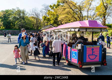 Der Osaka Road Train am Bahnhof Gokurakubashi im Osaka Castle Park an einem sonnigen Frühlingstag. Gäste, die vom beliebten Shuttleservice aussteigen. Stockfoto