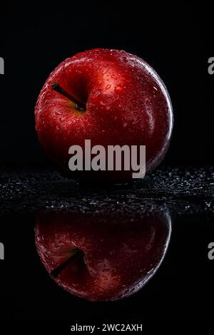 Roter Apfel mit Wassertropfen auf schwarzem Hintergrund Stockfoto