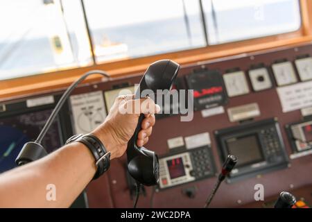 Navigationsbedienfeld und UKW-Funkgerät mit Hand. Funkkommunikation auf See. Arbeiten an der Schiffsbrücke. Stockfoto