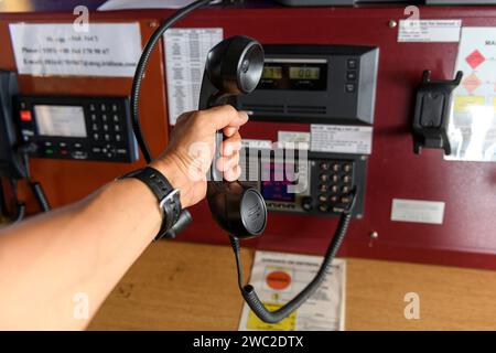 Navigationsbedienfeld und UKW-Funkgerät mit Hand. Funkkommunikation auf See. Arbeiten an der Schiffsbrücke. Stockfoto
