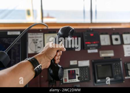 Navigationsbedienfeld und UKW-Funkgerät mit Hand. Funkkommunikation auf See. Arbeiten an der Schiffsbrücke. Stockfoto