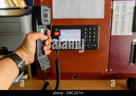 Navigationsbedienfeld und UKW-Funkgerät mit Hand. Funkkommunikation auf See. Arbeiten an der Schiffsbrücke. Stockfoto