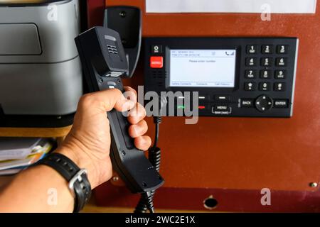 Navigationsbedienfeld und UKW-Funkgerät mit Hand. Funkkommunikation auf See. Arbeiten an der Schiffsbrücke. Stockfoto