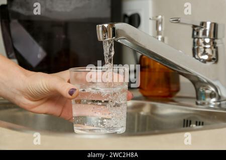 Füllen Sie ein Glas mit frischem Trinkwasser aus dem Küchenarmatur Stockfoto