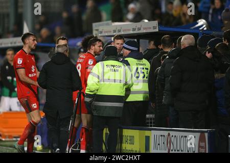 Birkenhead, Großbritannien. Januar 2024. Michael Williamson, der Milton Keynes Dons Manager (c), sieht zu, wie Fans, Spieler und Management um das Dugout des Auswärtsteams streiten. EFL Skybet Football League Two Match, Tranmere Rovers gegen MK Dons im Prenton Park, Birkenhead, Wirral am Samstag, den 13. Januar 2024. Dieses Bild darf nur für redaktionelle Zwecke verwendet werden. Nur redaktionelle Verwendung, .PIC von Chris Stading/ Credit: Andrew Orchard Sportfotografie/Alamy Live News Stockfoto