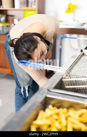 Junge Frau, die arbeitet, eine Industrieküche für Fast Food anstellt, Lebensstil am Arbeitsplatz, Hausarbeit Stockfoto