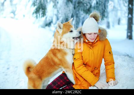 Ein Mädchen mit ihrem japanischen Akita-Inu-Hund für einen Spaziergang auf einem Feld im Winter. Stockfoto