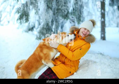 Ein Mädchen mit ihrem japanischen Akita-Inu-Hund für einen Spaziergang auf einem Feld im Winter. Stockfoto