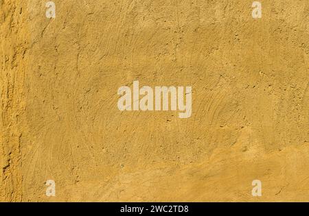 Fragment einer mit orangefarbener Farbe gemalten Wand. Keine flache Wand... Stockfoto