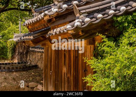 Keramikfliesen auf dem Dach eines Holztores im öffentlichen Park mit traditioneller koreanischer Architektur Stockfoto