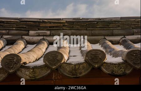 Großaufnahme des asiatischen Keramikdachs am Wintertag nach Schneefall mit blauem Himmel im Hintergrund Stockfoto