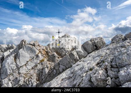 Bergsteiger auf dem felsigen Gipfel der Watzmann Mittelspitze mit Gipfelkreuz, Watzmann-Kreuzung, Nationalpark Berchtesgaden, Berchtesgadener Alpen Stockfoto