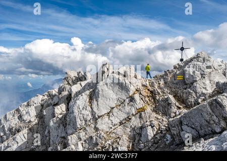 Bergsteiger auf dem felsigen Gipfel der Watzmann Mittelspitze mit Gipfelkreuz, Watzmann-Kreuzung, Nationalpark Berchtesgaden, Berchtesgadener Alpen Stockfoto