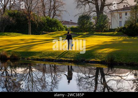 Weibliche Golferin reflektiert und sucht nach Golfbällen im Wasserteich auf dem Golfplatz in der Schweiz Stockfoto