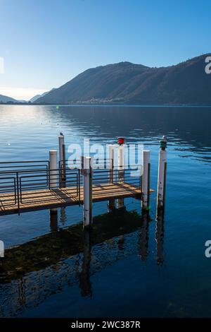 Bootsanleger auf dem Luganer See mit Berg und Sonnenlicht gegen den blauen klaren Himmel in Campione d'Italia, Lombardei, Italien Stockfoto