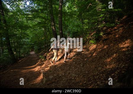 Wandern Sie einen Berg hinauf. Mom und Tochter gehen auf einem Pfad in einem steilen Hügel. Brasov, Berg Rumänien. Stockfoto