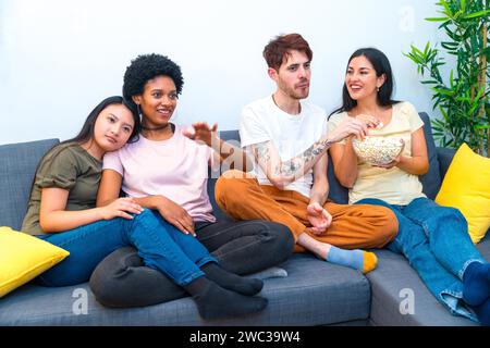 Verschiedene Freunde schauen sich einen Film an, sitzen zusammen auf dem Sofa in einer Wohnung Stockfoto