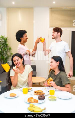 Vertikales Foto einer Gruppe multiethnischer Freunde, die beim Frühstück zu Hause genießen und feiern Stockfoto