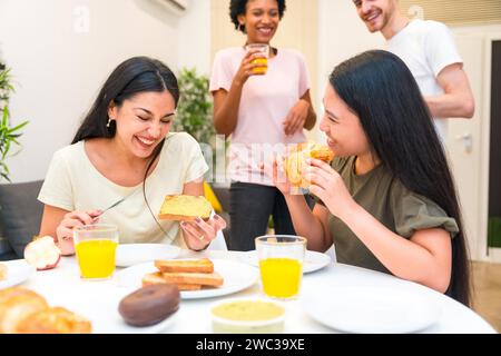 Gruppe von verschiedenen multiethnischen Freunden lacht beim Frühstück zu Hause Stockfoto