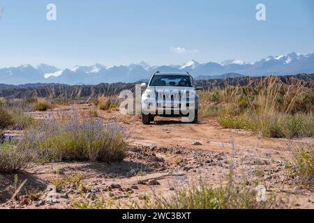 Geländewagen auf Geländestraßen, Badlands, Berge dahinter, in der Nähe von Bokonbayevo, Yssykkoel, Kirgisistan Stockfoto