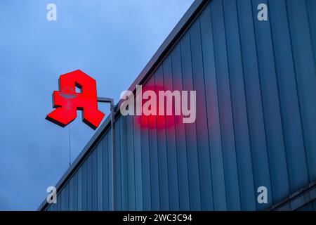 Beleuchtetes Apothekenschild vor stürmischem Himmel an einer Fassade in Düsseldorf Stockfoto