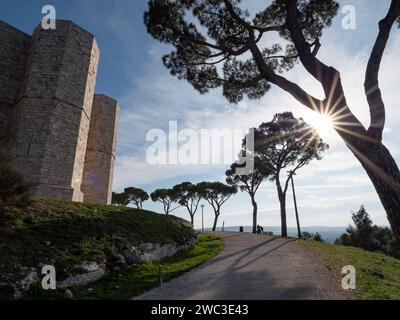 ANDRIA, ITALIEN - 30. OKTOBER 2021: Sonnenuntergang mit Sonnenstrahlen durch den Baum und das Wahrzeichen des Castel del Monte Stockfoto