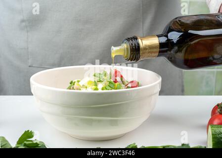 Gießen Sie Olivenöl über frischen Gemüsesalat, gesunde Lebensmittel Zutaten. Hausmannskost. Stockfoto