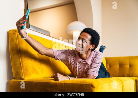 Fließender junger Mann, der zu Hause Crossdressing trägt, LGBTQ- und Diversity-Konzepte - hispanisches nicht binäres männliches Porträt in einer bunten Wohnung Stockfoto