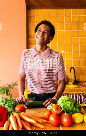 Fließender junger Mann, der zu Hause Crossdressing trägt, LGBTQ- und Diversity-Konzepte - hispanisches nicht binäres männliches Porträt in einer bunten Wohnung Stockfoto