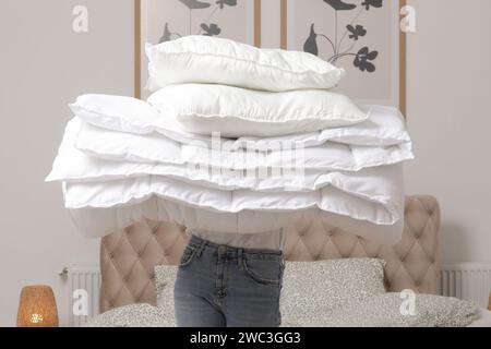Frau, die einen Haufen weicher weißer gefalteter Bettdecken und Kissen zu Hause in ihrem Schlafzimmer hält, gemütlicher Lebensstil, Hausfrauen-Reinigung, Aufräumen des Schlafzimmers, hä Stockfoto