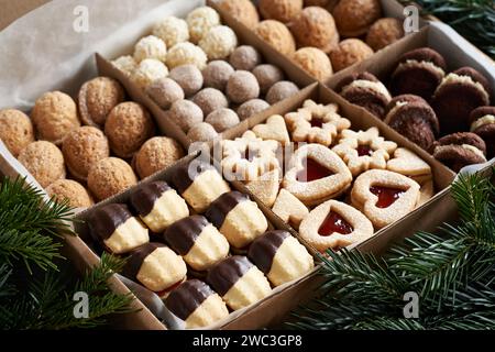 Mischung aus hausgemachten Weihnachtskeksen in einer Geschenkbox auf einem Tisch mit Tannenzweigen Stockfoto