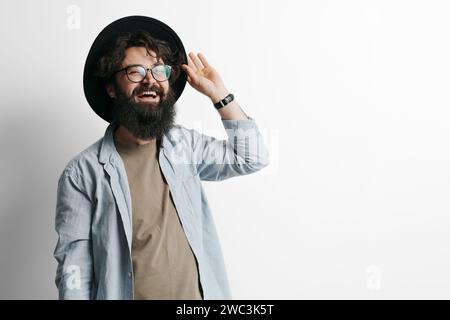 Fröhlicher bärtiger Mann in Hut Gruß mit einer Handerhöhung Stockfoto