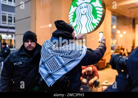 Pro-Palästinensische Demo in Berlin ca. 1000 Menschen nahmen am 13.01.2024 an einer Pro-Palästinensischen Demo Teil. Unter dem Motto Solidarität mit Palästina liefen die Teilnehmer vom Neptunbrunnen zum Potsdamer Platz. Neben Freiheit für Palästina, Freiheit für Gaza, waren auch immer wieder rufe wie Deutschland finanziert, Israel bombardiert und Stoppt den Völkermord zu hören. Insgesamt war die Stimmung sehr Pressefeindlich und oft waren Parolen wie Lasst euch nicht betrügen, deutsche Medien lügen zu hören. Hier im Bild läuft die Demo an einem Starbucks vorbei. Von Seiten der Demo wird darauf Stockfoto