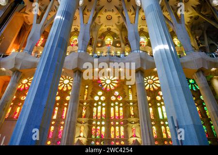 Flacher Innenanblick des Lichts, das durch entworfene Buntglasfenster in der Basilika La Sagrada Familia von Antoni Gaudí, Barcelona, Spanien scheint Stockfoto