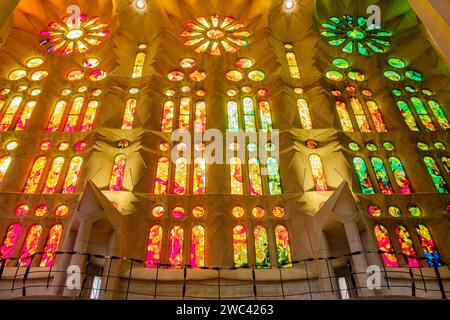 Flacher Innenanblick des Lichts, das durch entworfene Buntglasfenster in der Basilika La Sagrada Familia von Antoni Gaudí, Barcelona, Spanien scheint Stockfoto