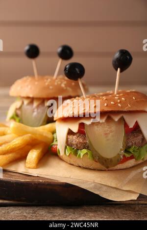 Süße Monster Burger serviert mit Pommes frites auf Holztisch, Nahaufnahme. Halloween Party Essen Stockfoto