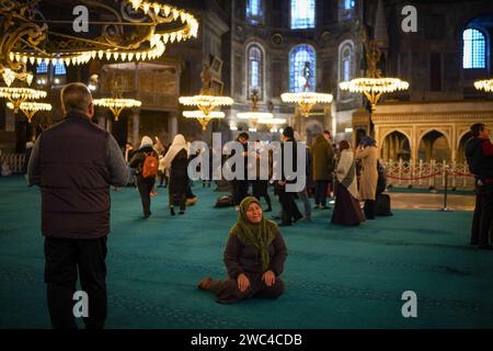 Istanbul, Türkei. Januar 2024. Eine Frau sitzt auf dem Boden, während sie für die Kamera in Hagia Sophia posiert. Die Hagia Sophia, wurde 2020 durch den Beschluss von Präsident Erdogan von einem Museum in eine Moschee umgewandelt, Besucher, die Touristen sind, werden ab 15. Januar 2024 eine Gebühr von 25 Euro, durch die Entscheidung des Ministeriums für Kultur und Tourismus. Quelle: SOPA Images Limited/Alamy Live News Stockfoto