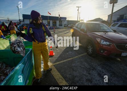 Richmond, Kanada. Januar 2024. Ein Freiwilliger bereitet sich darauf vor, einen Beutel Heringsfisch an einen Kunden zu übergeben, während der jährlichen Veranstaltung Fishing Helping Kids With Cancer Hering in einem Fischerhafen in Steveston Village in Richmond, British Columbia (BC), Kanada, am 13. Januar 2024. Lokale Fischer spendeten 75 Tonnen Heringsfische für den Verkauf während der Veranstaltung, um Kinder zu unterstützen, die im BC Children's Hospital wegen Krebs behandelt wurden. Quelle: Liang Sen/Xinhua/Alamy Live News Stockfoto