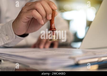 Geschäftsmann stempelt die Genehmigung auf einem Dokumentenzertifikat oder einem offiziellen Garantievertrag oder einer Visumgenehmigung am Schreibtisch Stockfoto