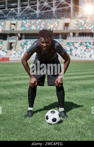 Selbstbewusster junger afroamerikanischer Fußballspieler, der im Stadion Fußball spielt Stockfoto