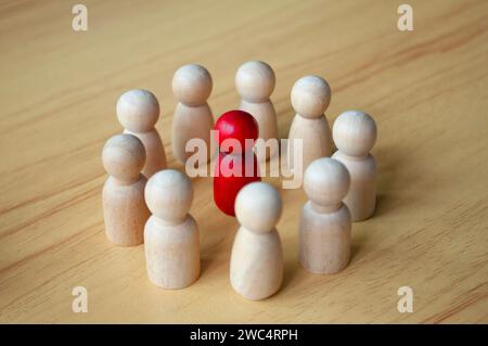 Nahaufnahme einer roten Holzpuppe, umgeben von anderen Puppen. Entweder Führung oder Belästigung vertreten. Stockfoto